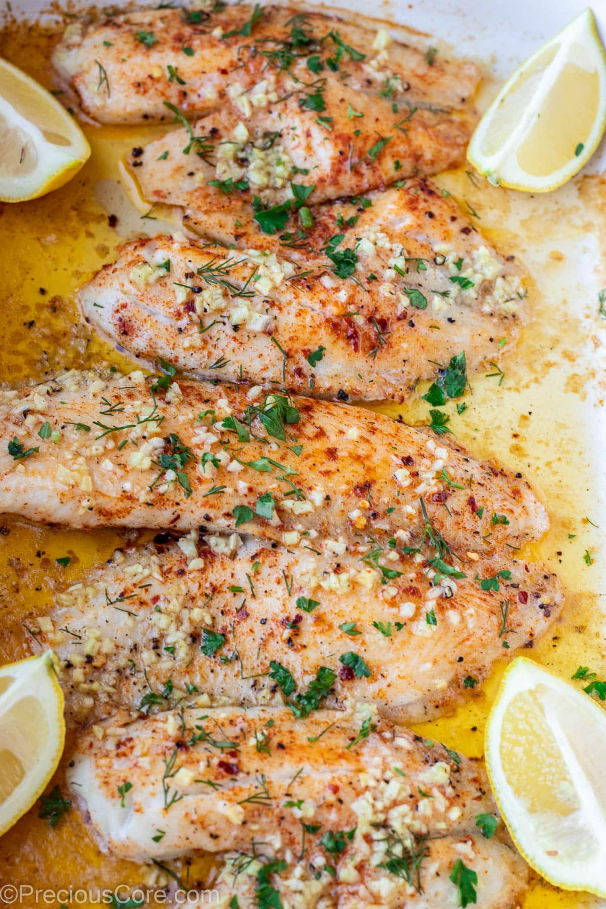 4 baked tilapia fillets in a pan.