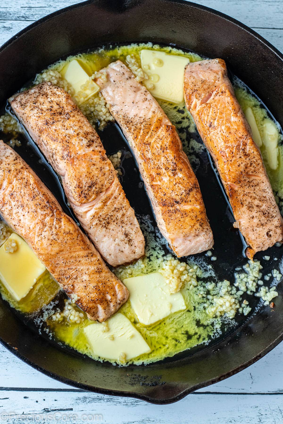 Butter and minced garlic in a cast iron skillet with seared salmon.