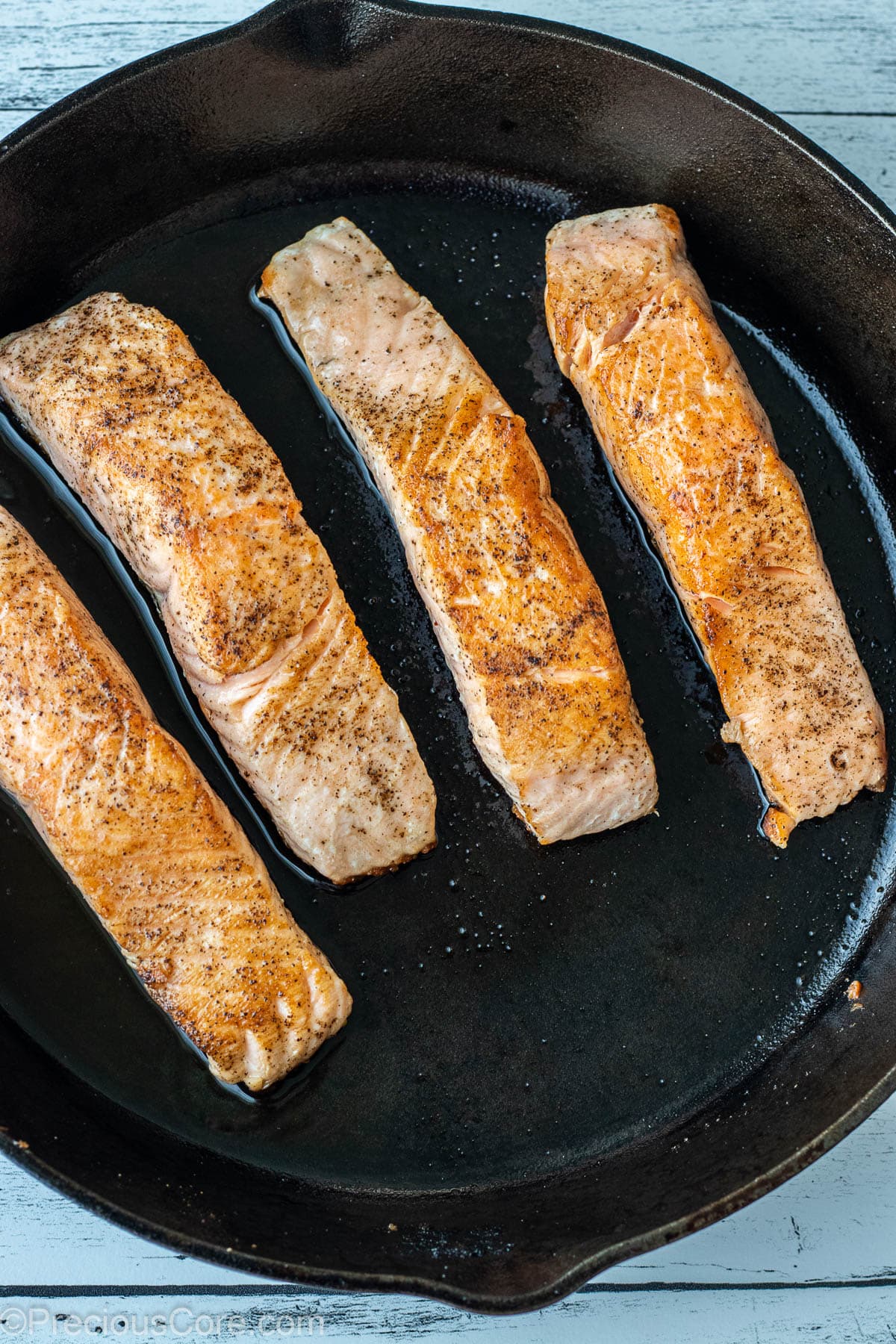Seared salmon fillets in a cast iron skillet.