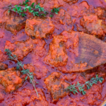 Tomato beef stew in a pot with text at the bottom that says, "Nigerian Beef Stew".