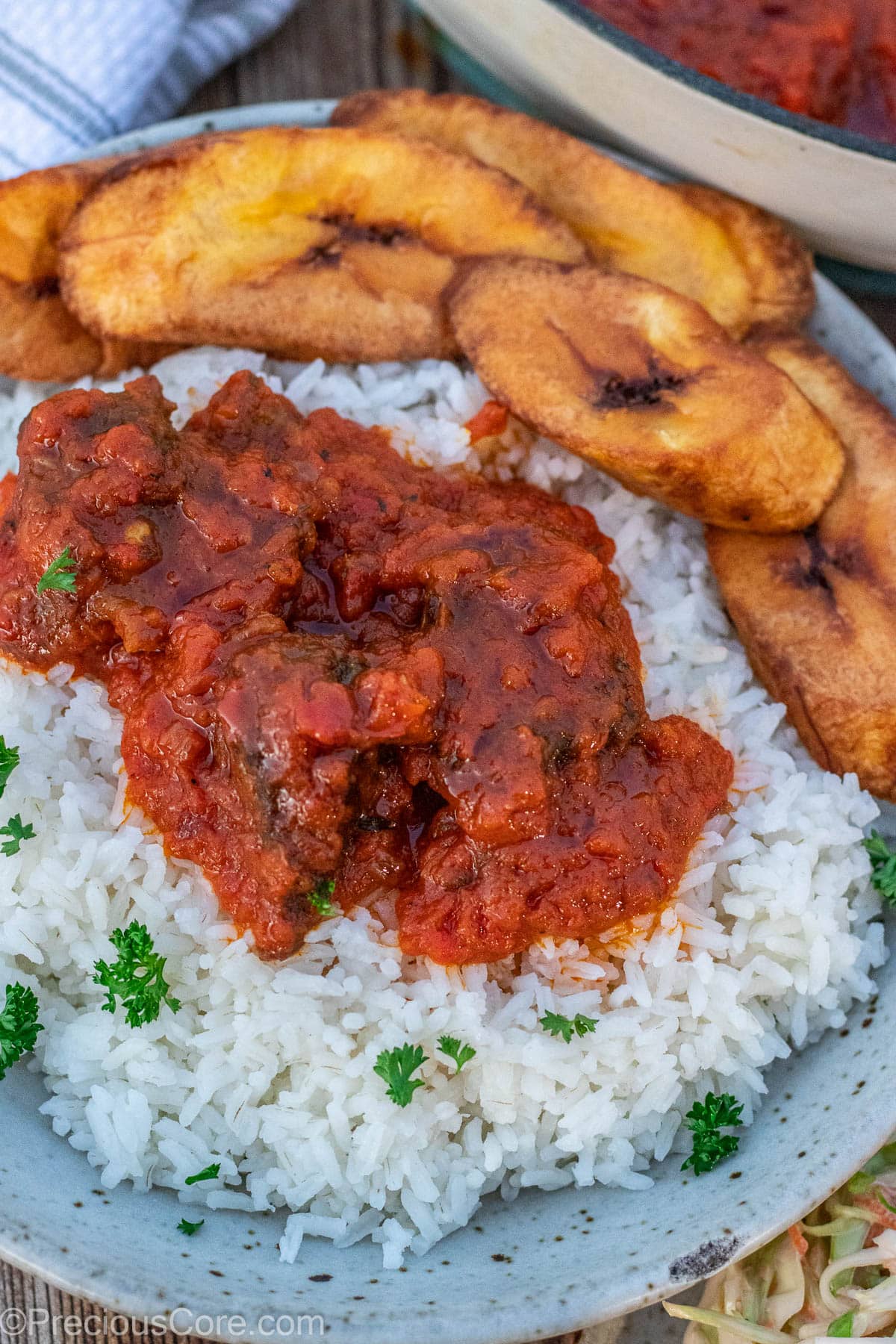 A bowl with rice, tomato stew, and plantains.
