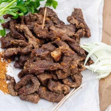 Cameroonian grilled meat on parchment paper, served with onions and soya pepper.