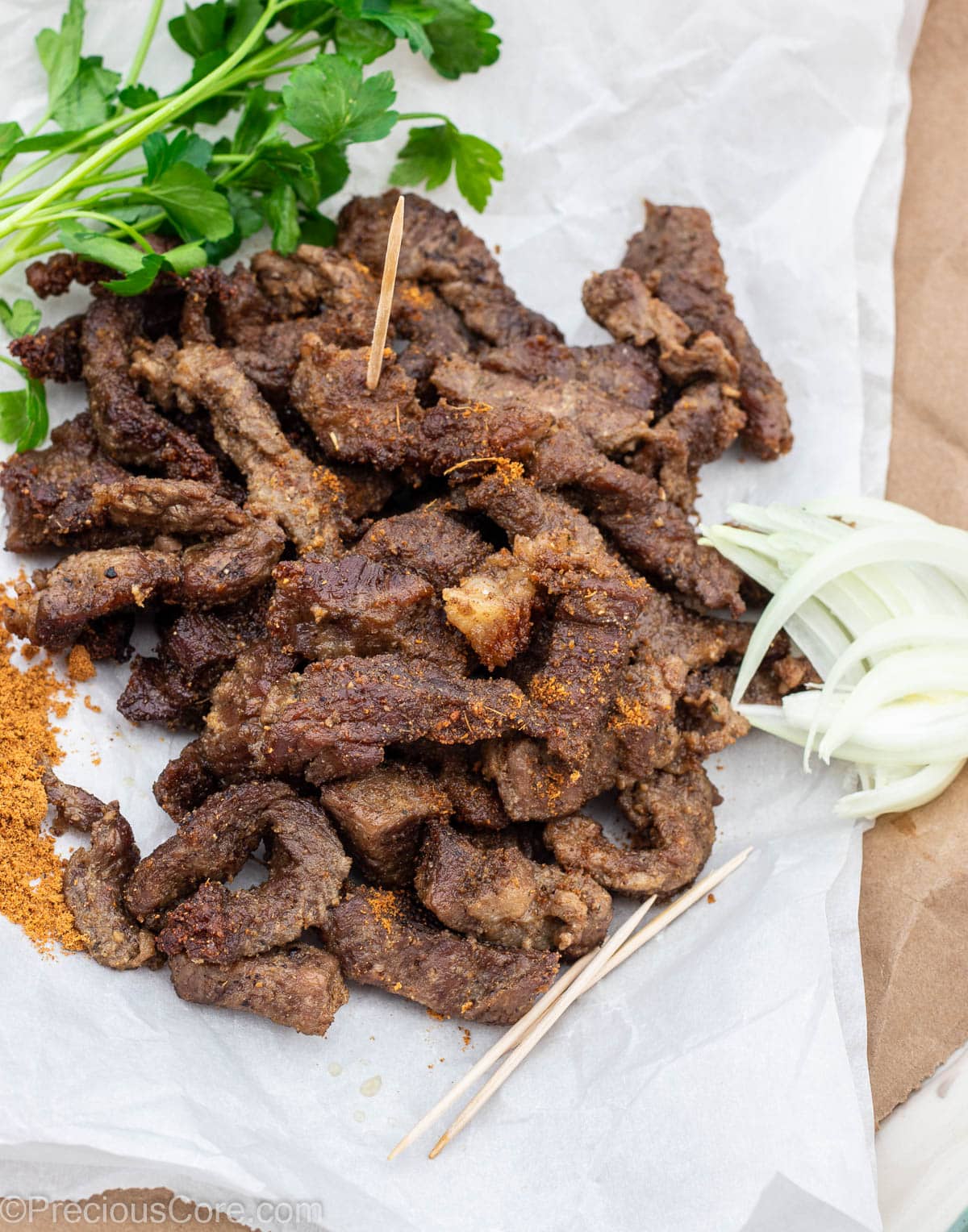 Cameroonian grilled meat on parchment paper, served with onions and soya pepper.