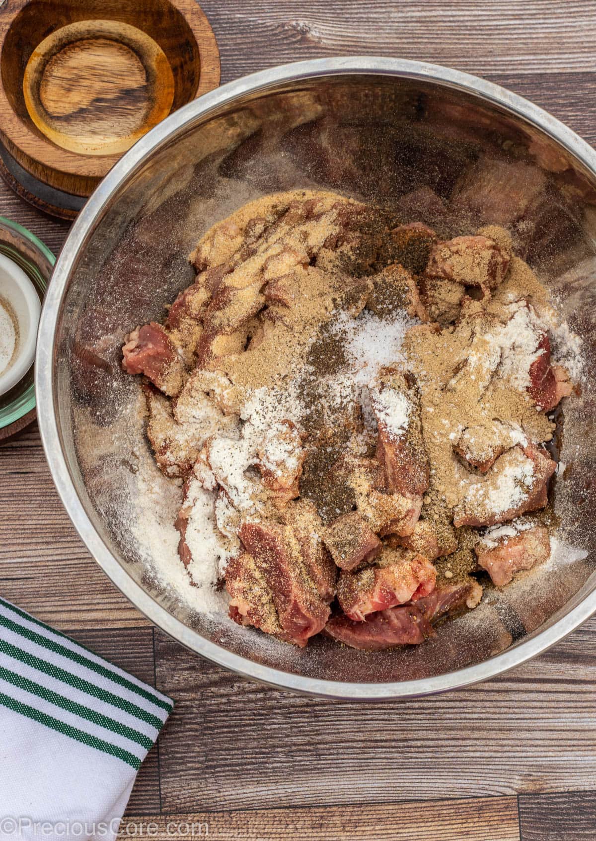 Beef in a bowl with oil and spices on top.