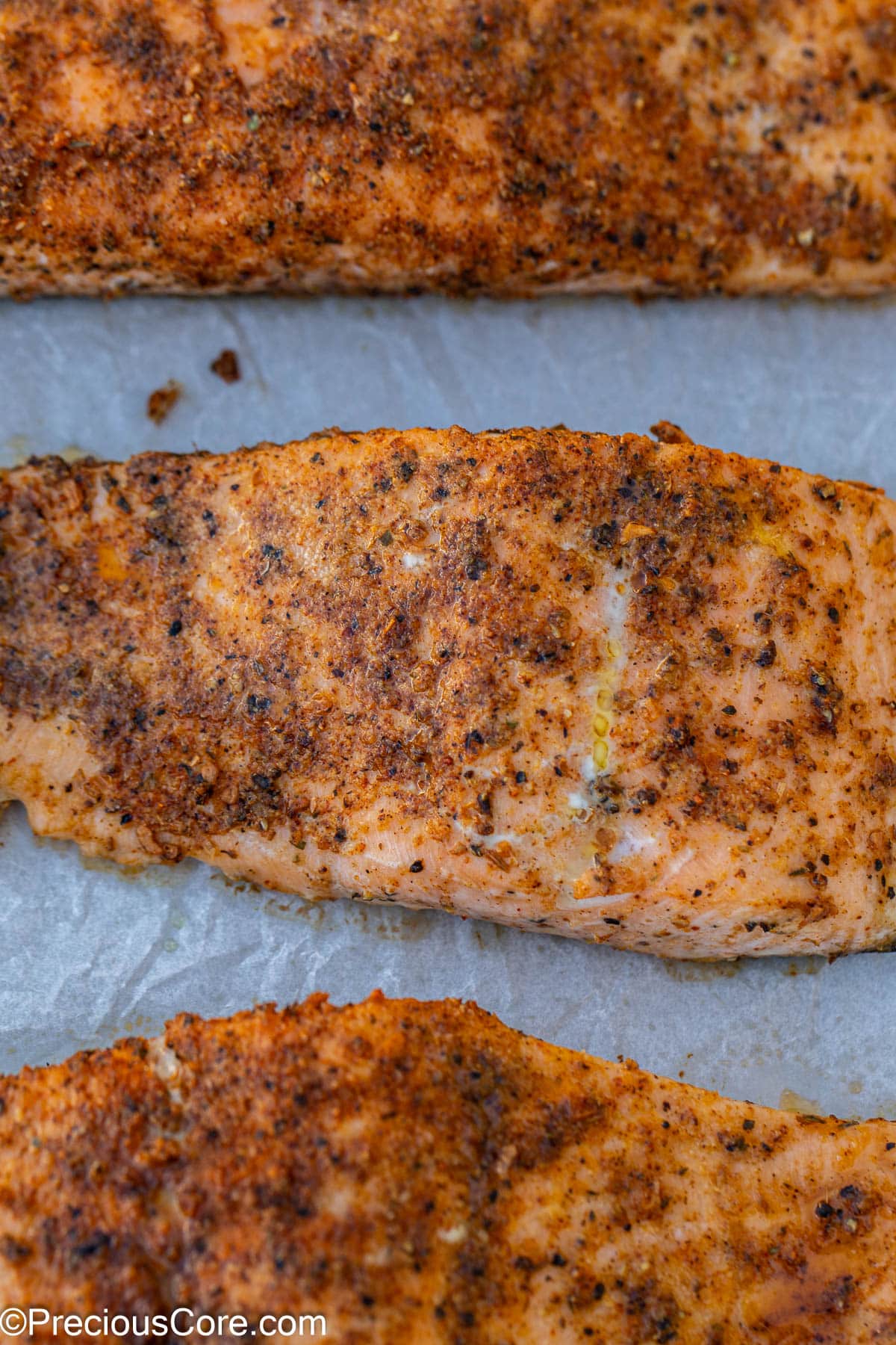 Baked Cajun salmon on parchment paper.