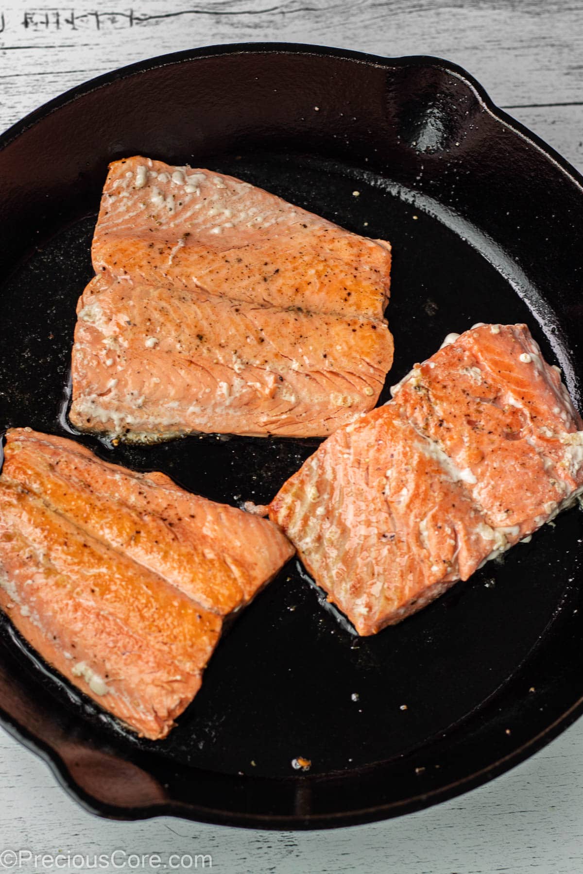 Pan fried salmon in pan.
