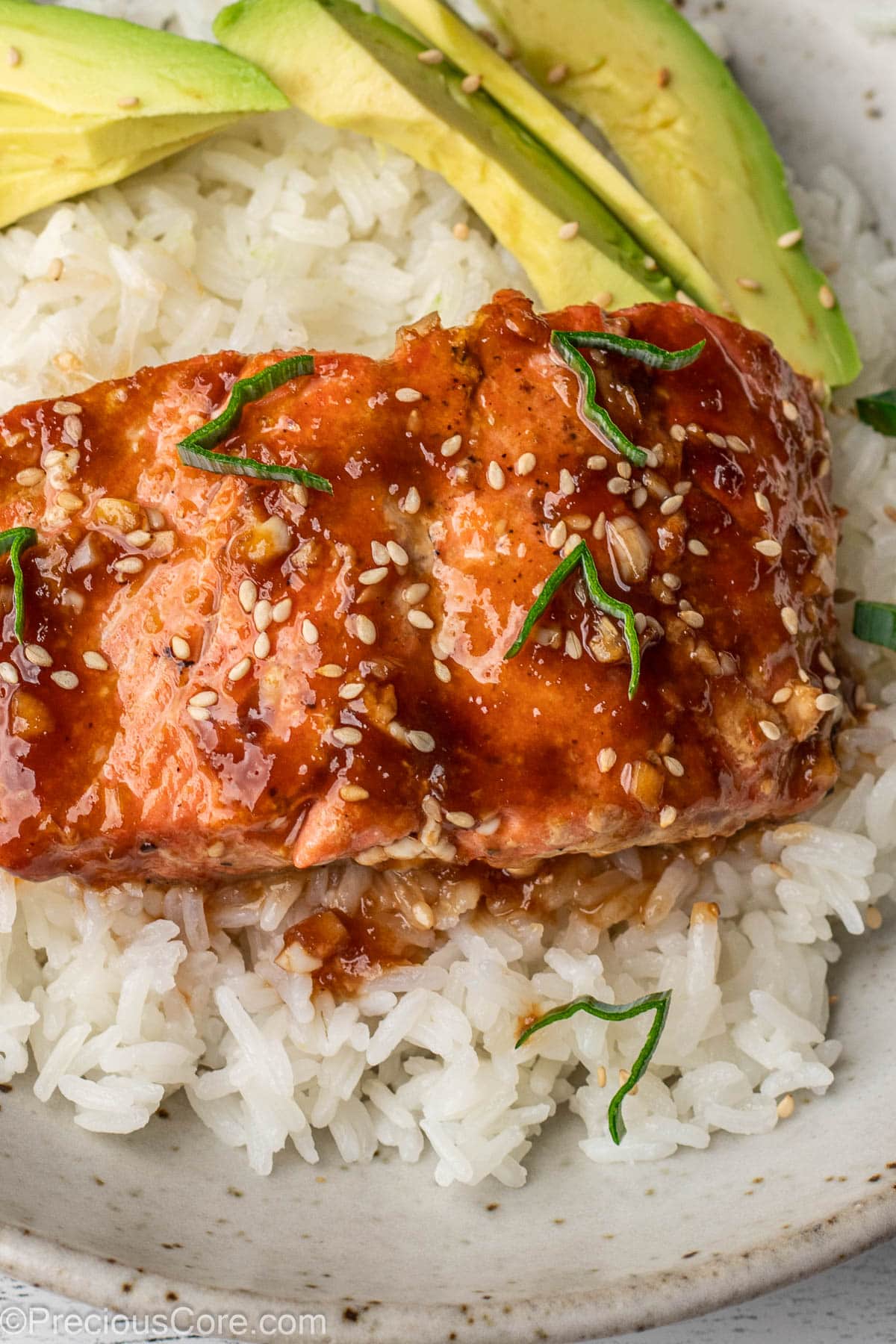 Teriyaki Salmon over rice with avocado slices in a bowl.