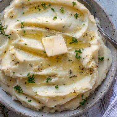 Rosemary Garlic Mashed Potatoes in a bowl topped with melted butter and parsley.