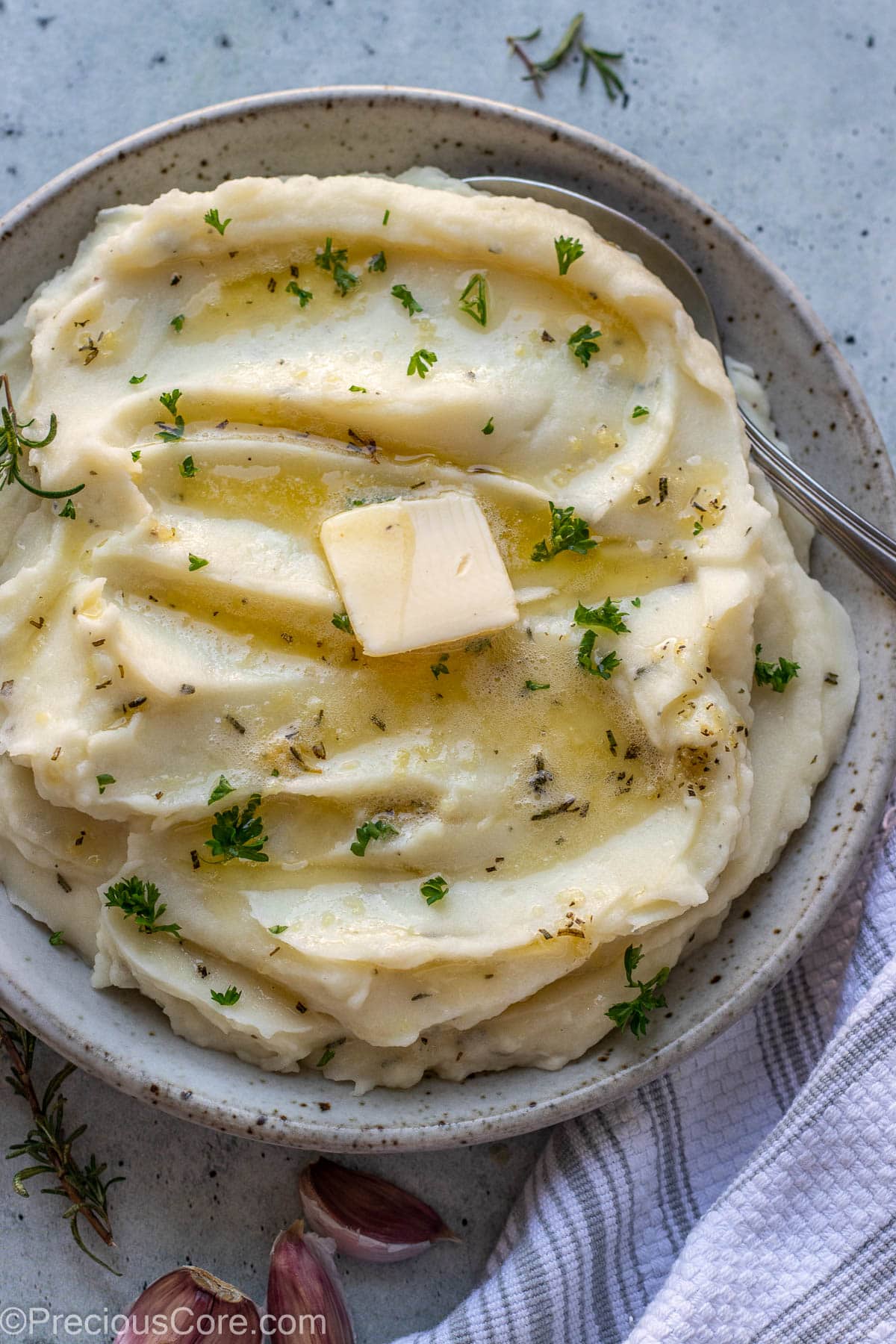 Rosemary Garlic Mashed Potatoes in a bowl topped with melted butter and parsley.