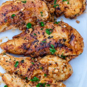 Pan seared chicken tenders on a white platter.