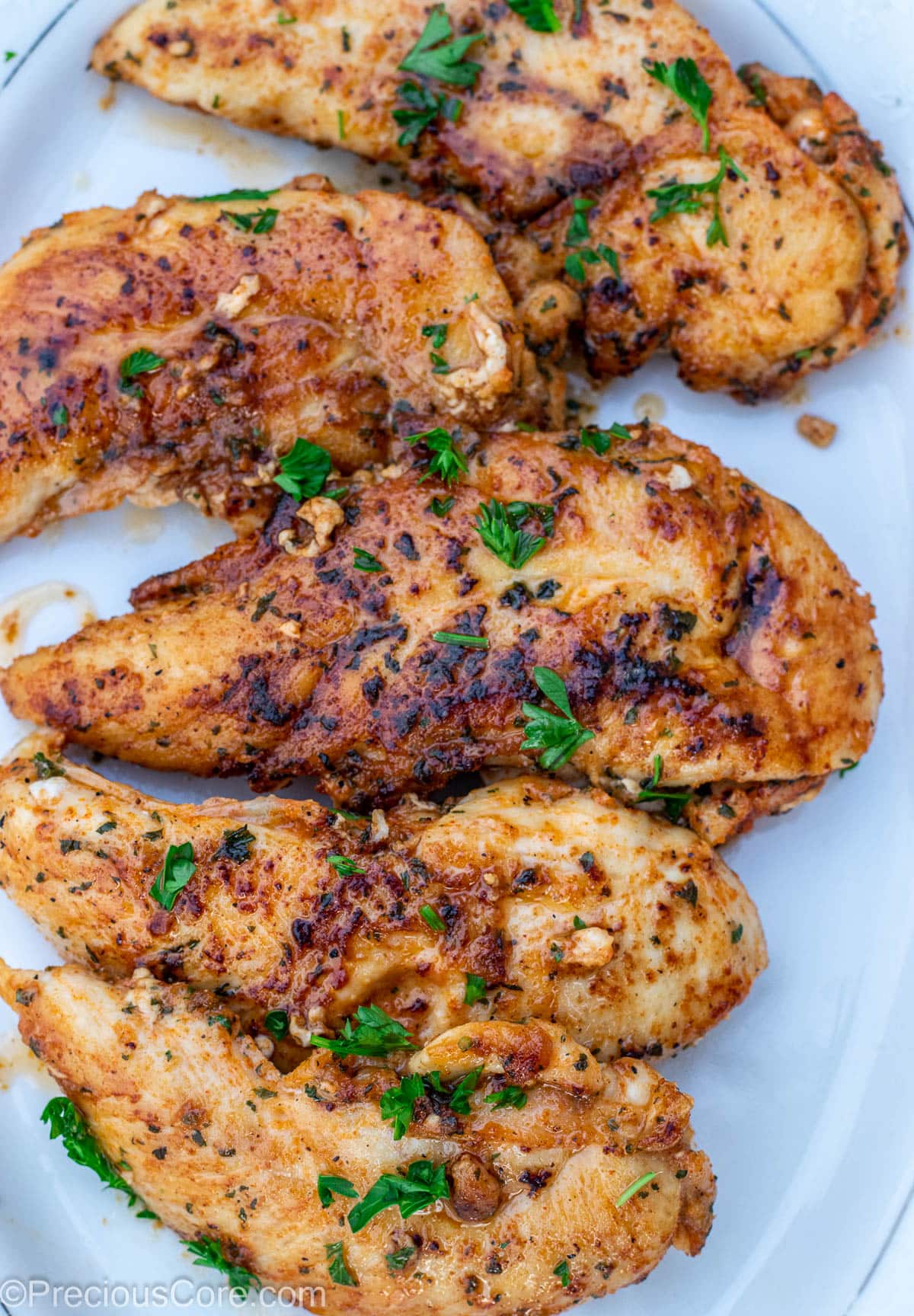 Pan seared chicken tenders on a white platter.