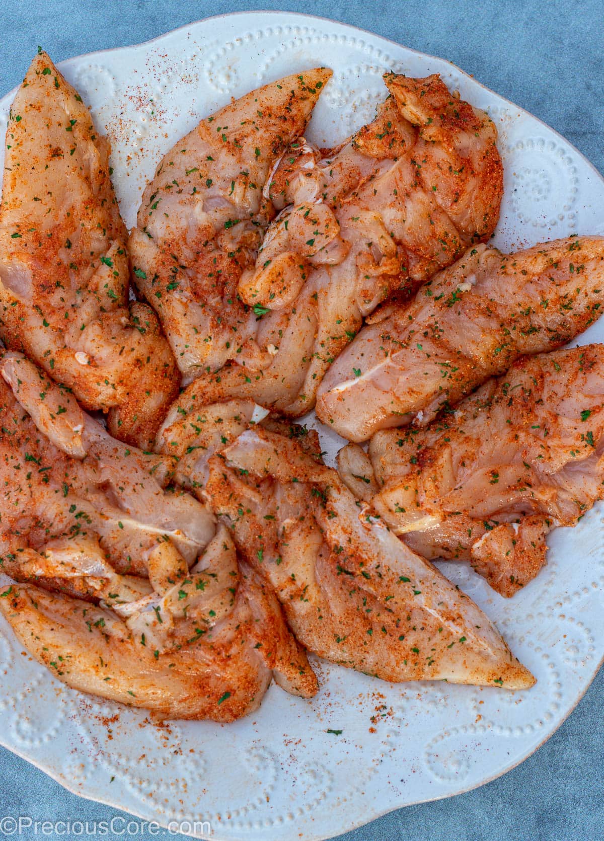 Seasoned chicken tenders on a white plate.