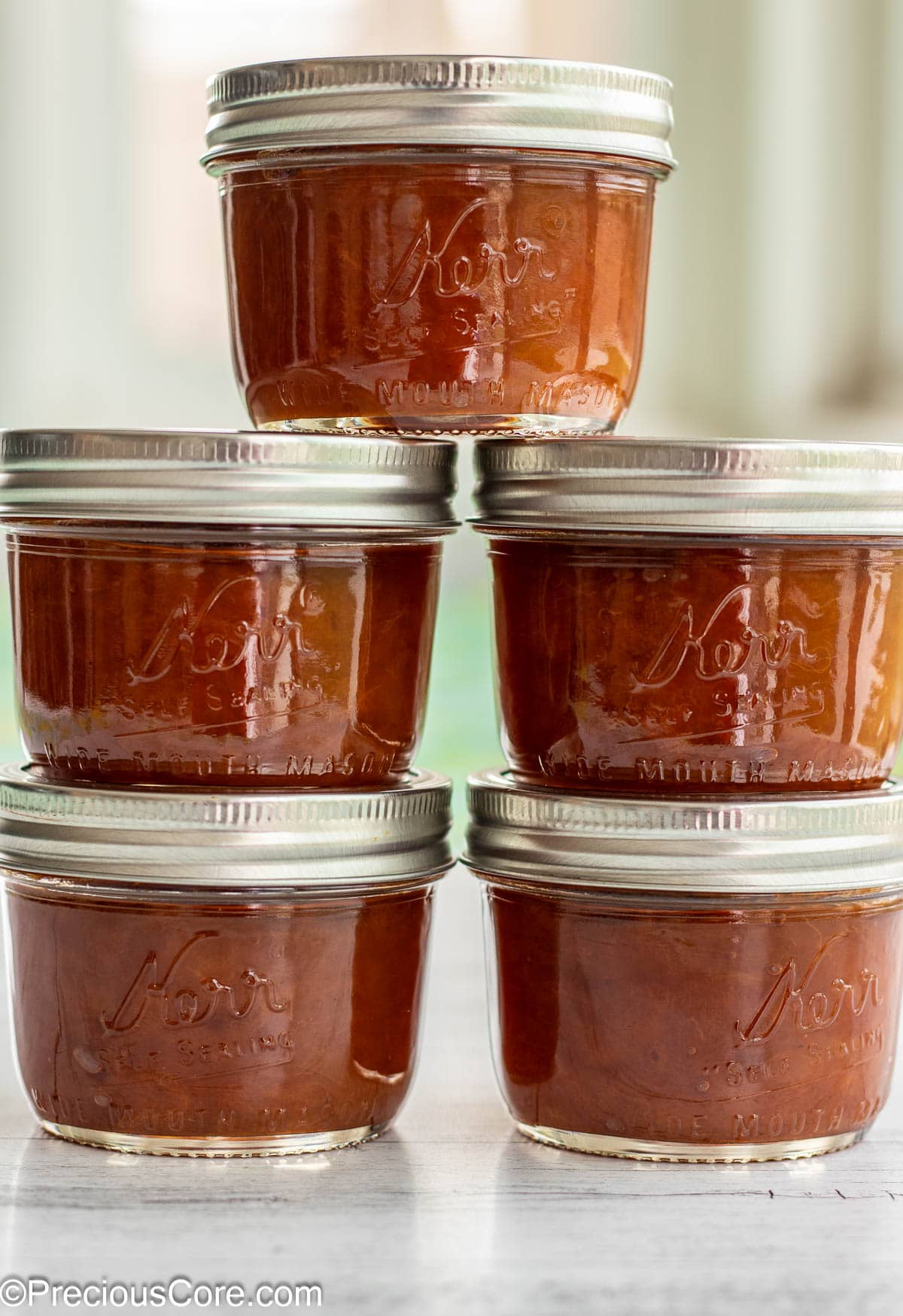 5 jars of fruit preserves stacked on each other.