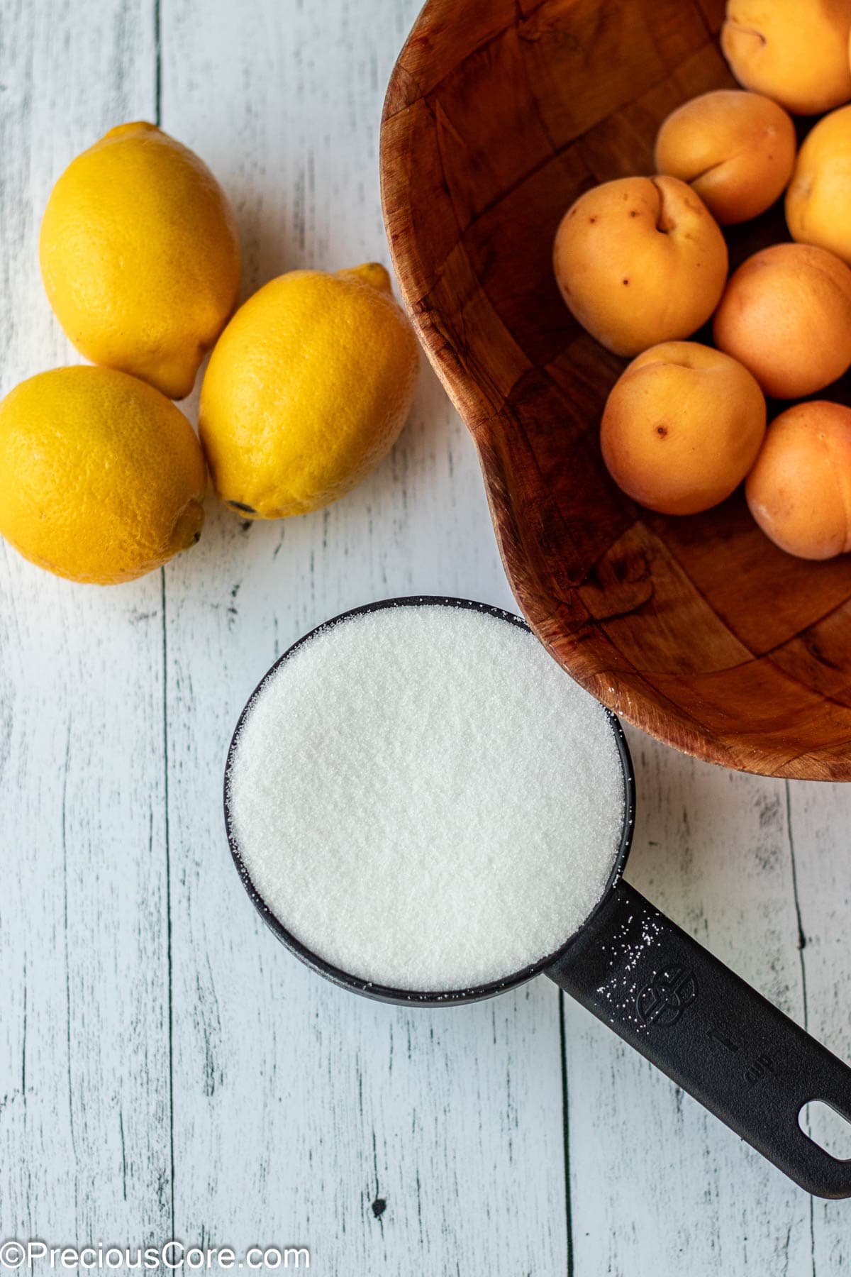 Apricots, lemon and sugar on a board.