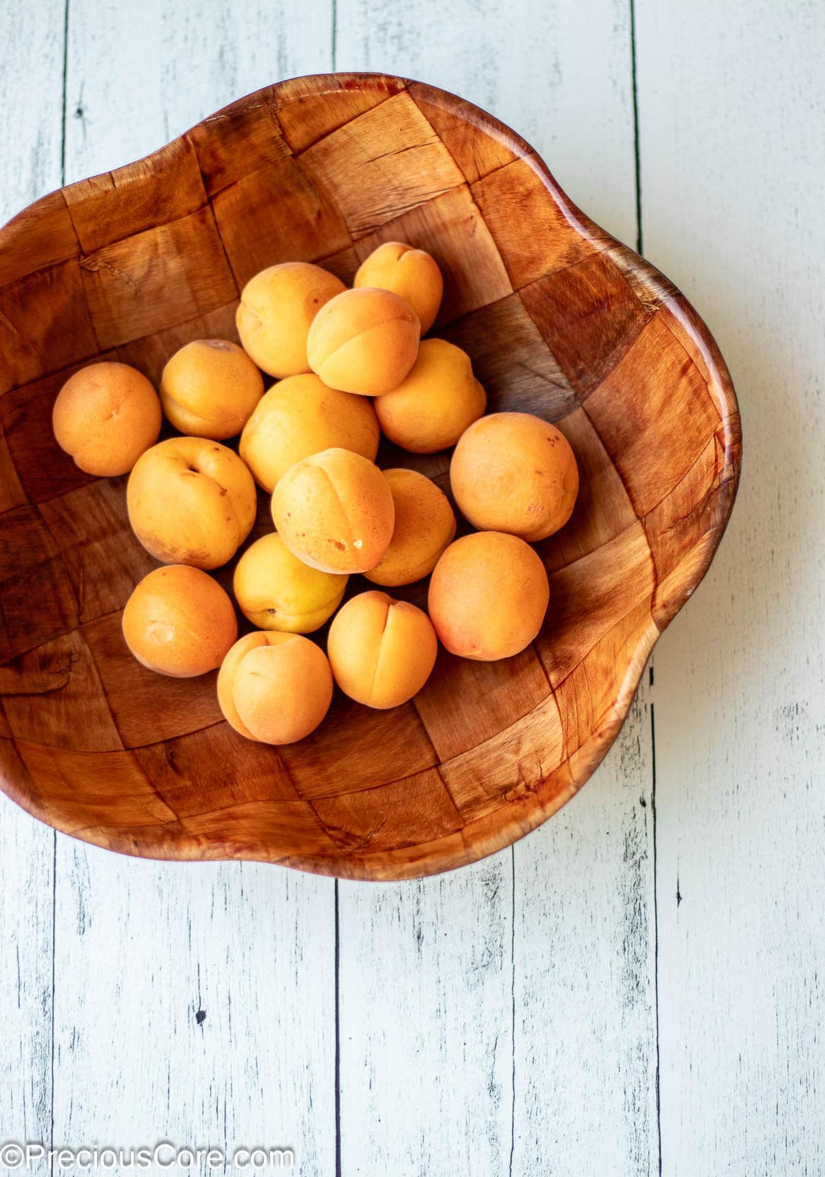 A wooden bowl of apricots.