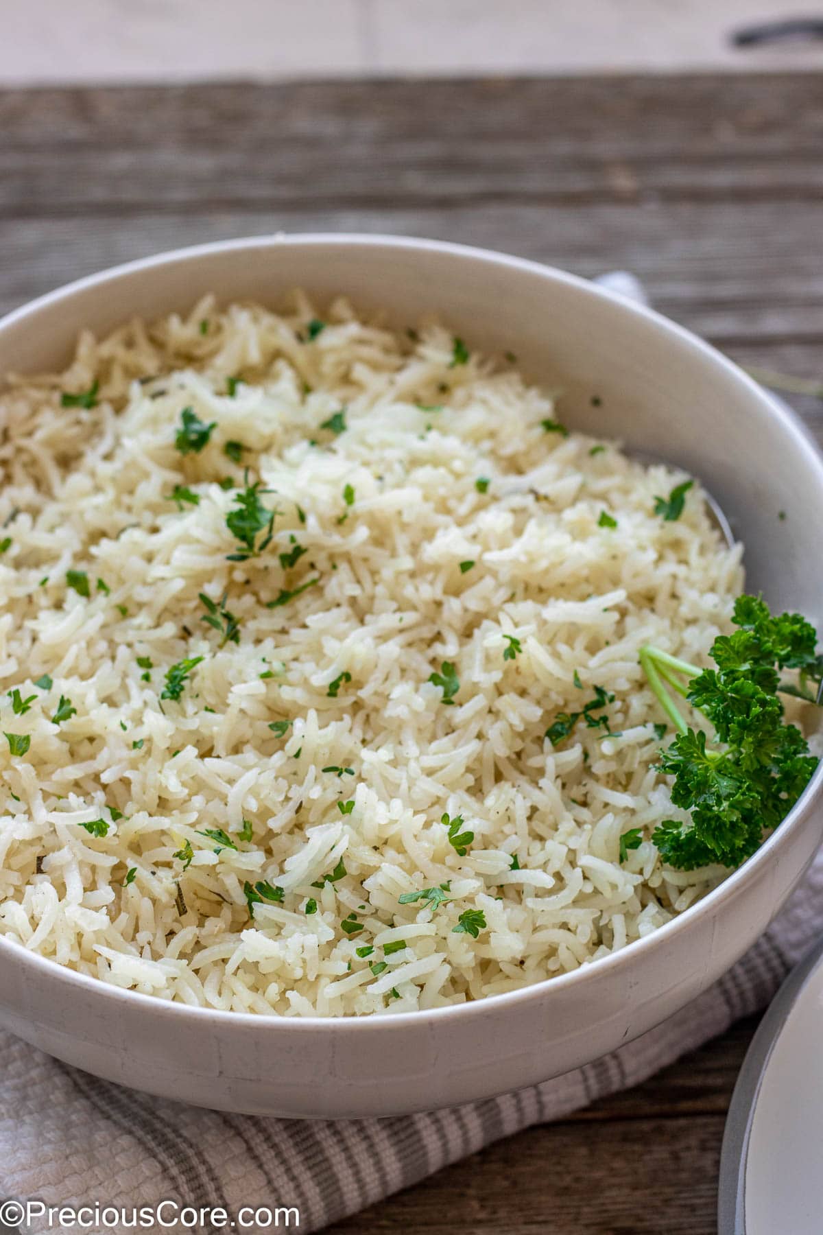 A bowl of garlic herb rice topped with minced fresh parsley.