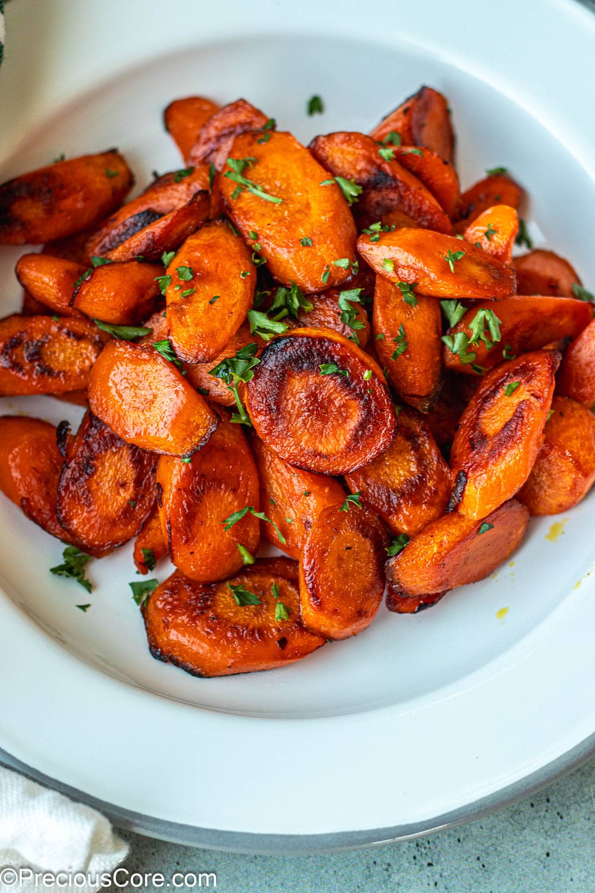 Carrots on a white plate garnished with parsley.