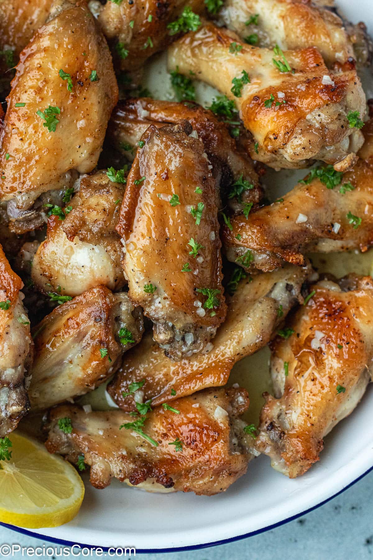 Bowl of chicken wings with garlic butter at the bottom.