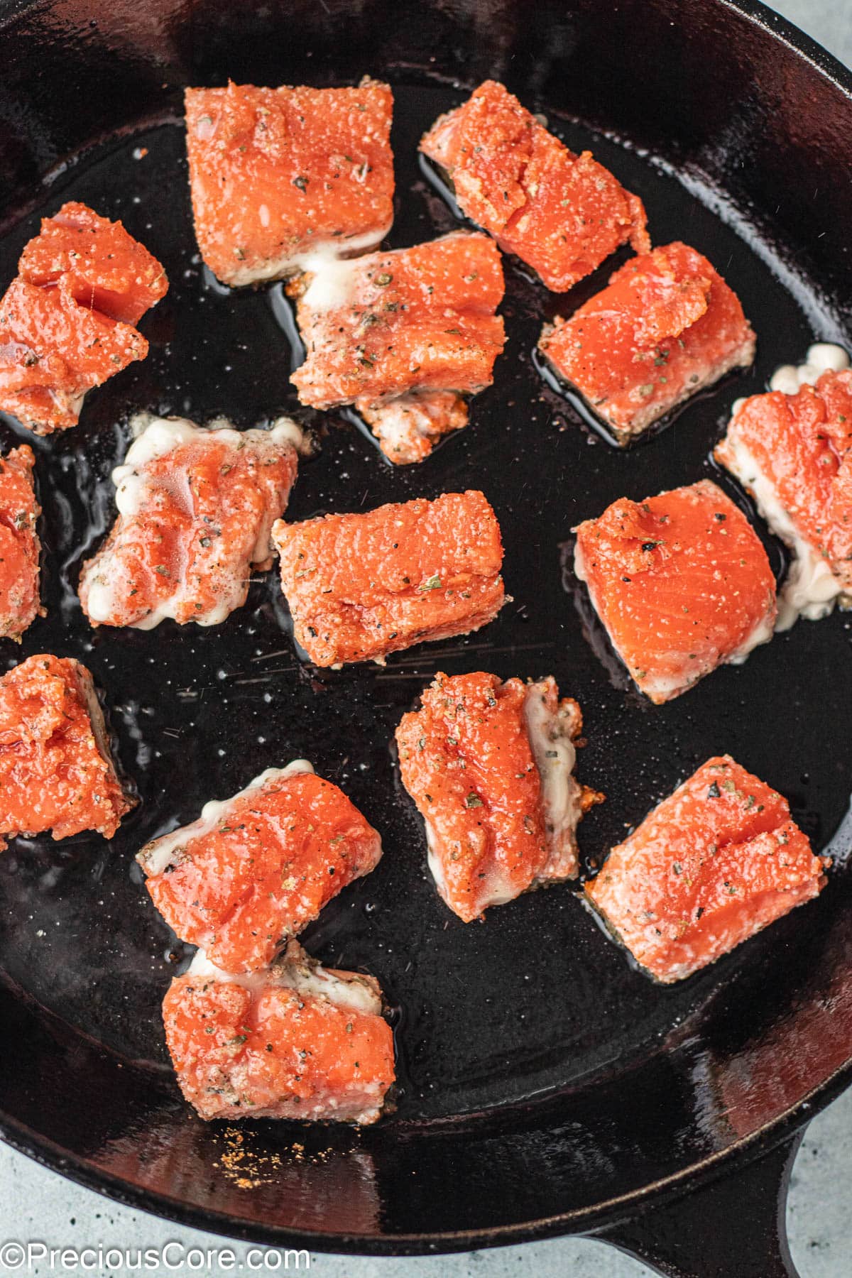 Salmon bites in a cast iron skillet.