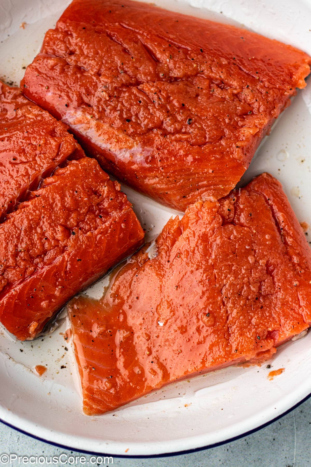 Seasoned salmon in a white bowl.