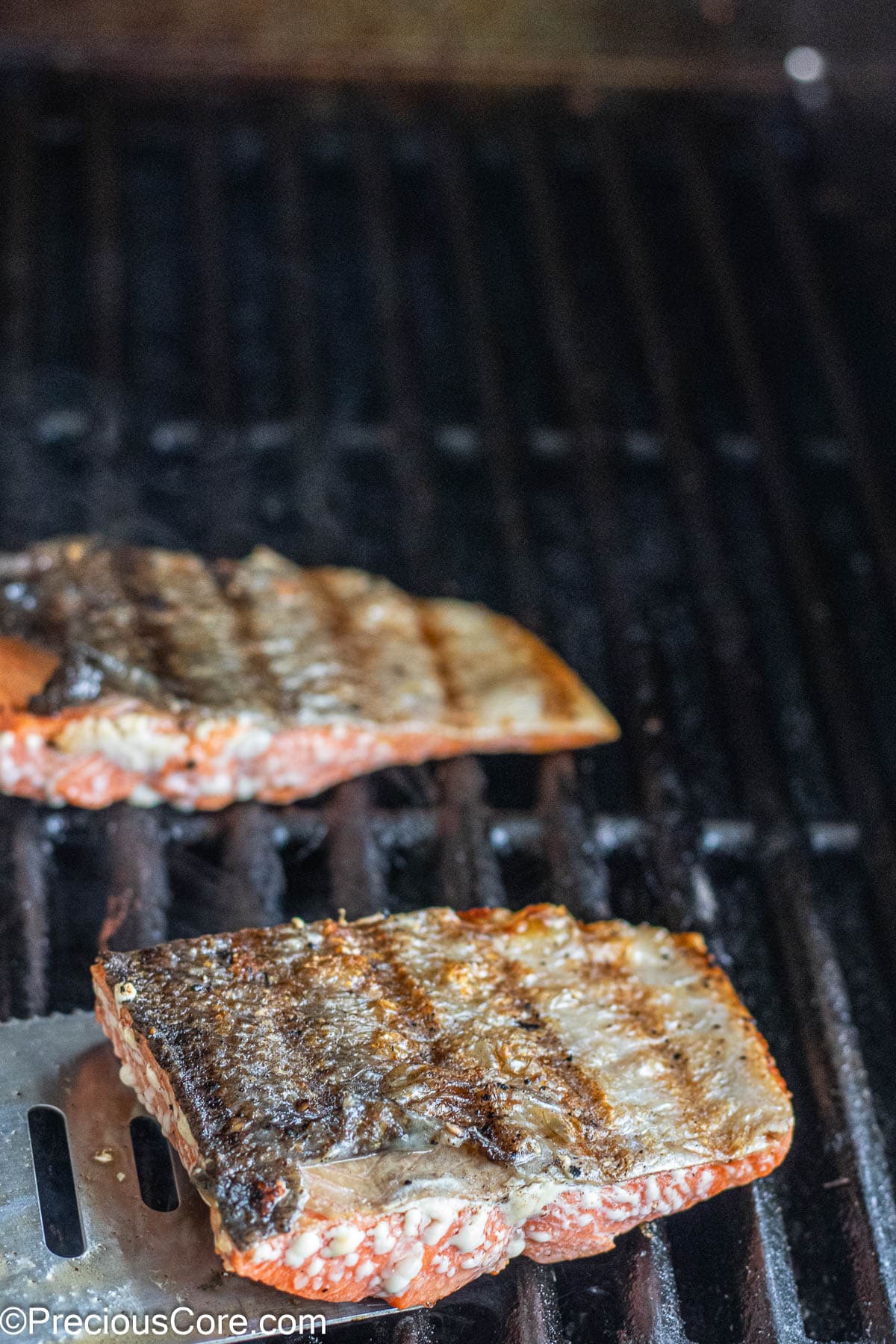 Skin-on sockeye salmon with grill marks on a grill.