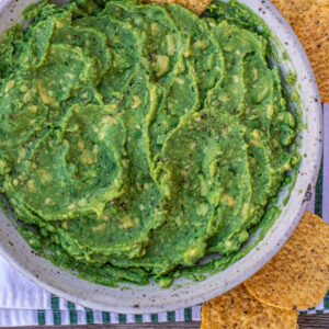 Guacamole in a bowl with a tortilla chip stuck in.