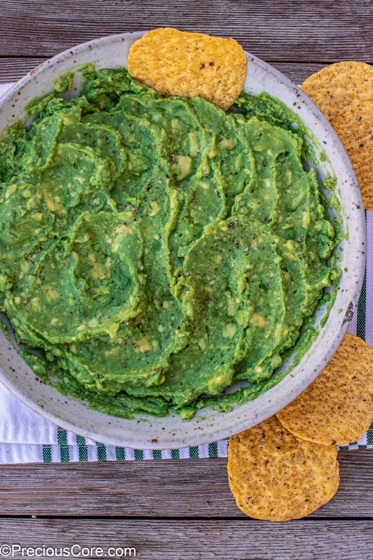 Guacamole in a bowl with a tortilla chip stuck in.