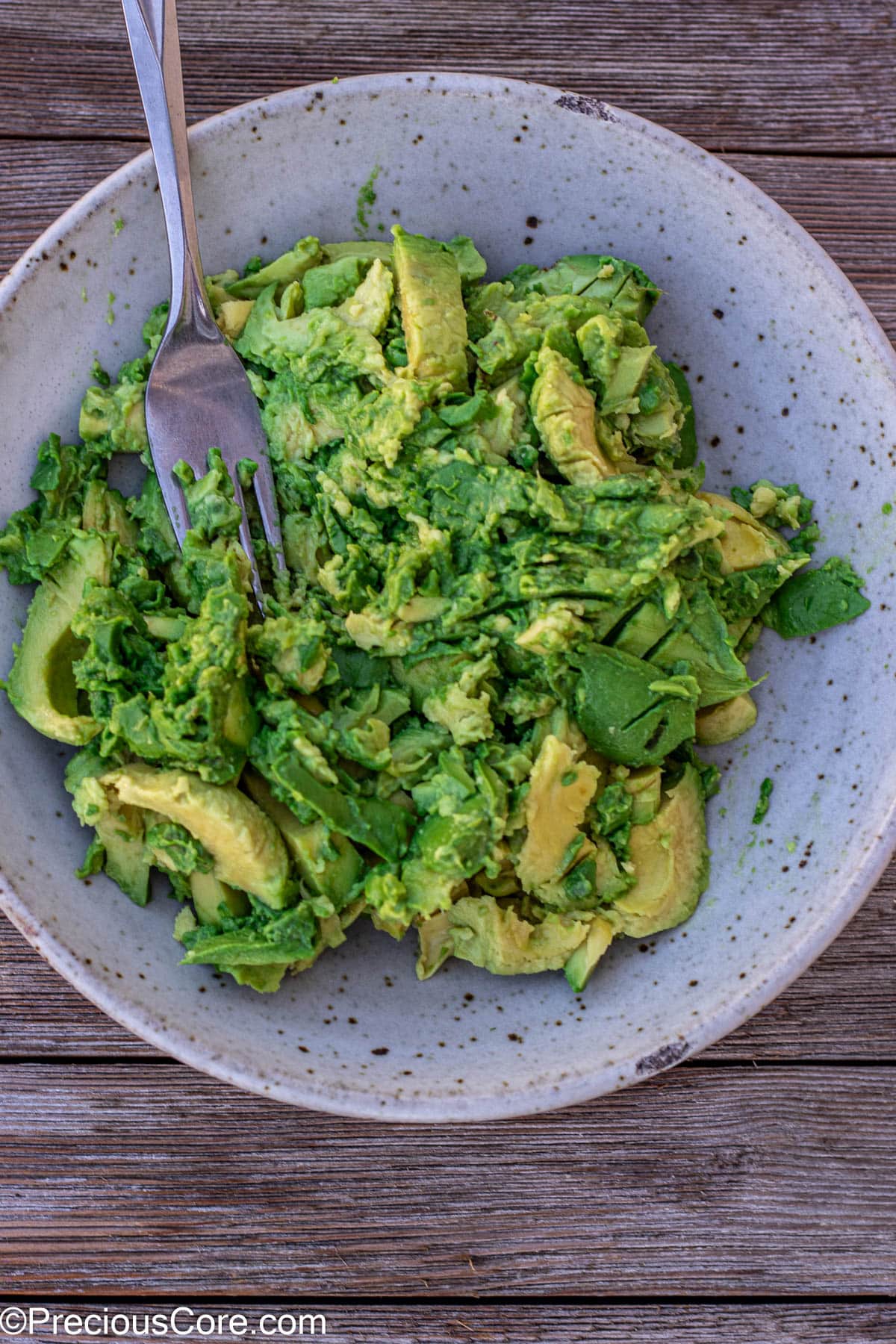 Mashing avocados with a fork.