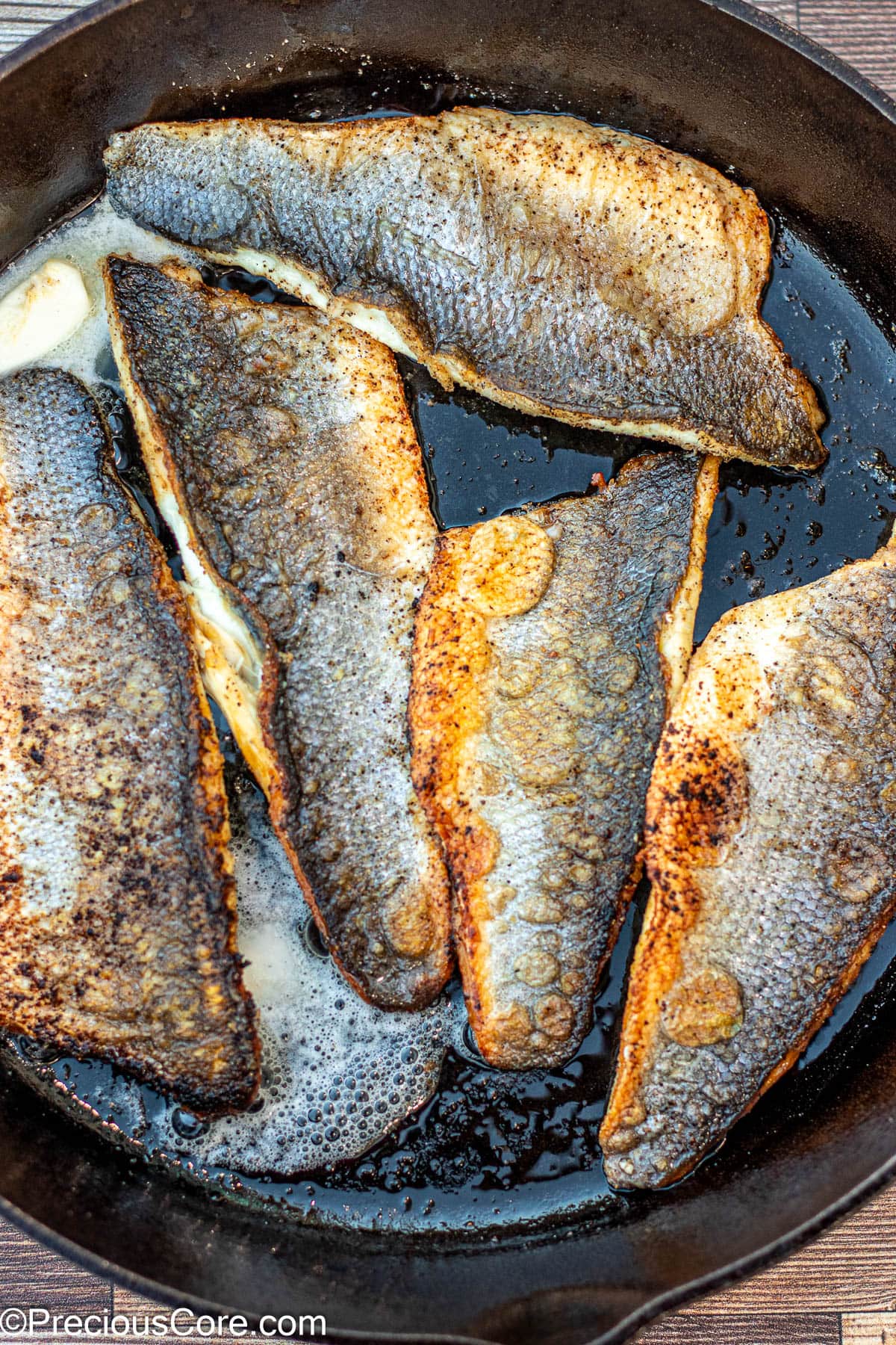 Butter melting in cast iron skillet with fish.