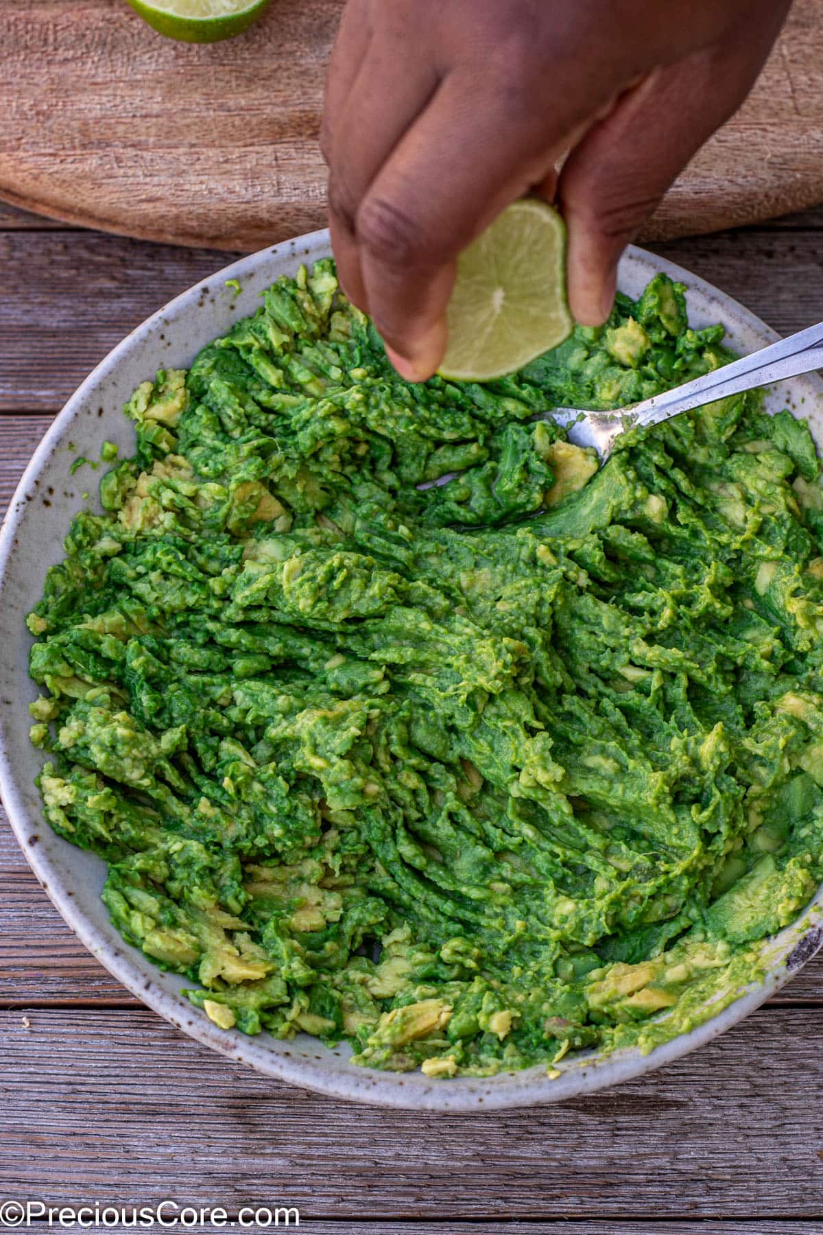 Squeezing lime juice into mashed avocados.