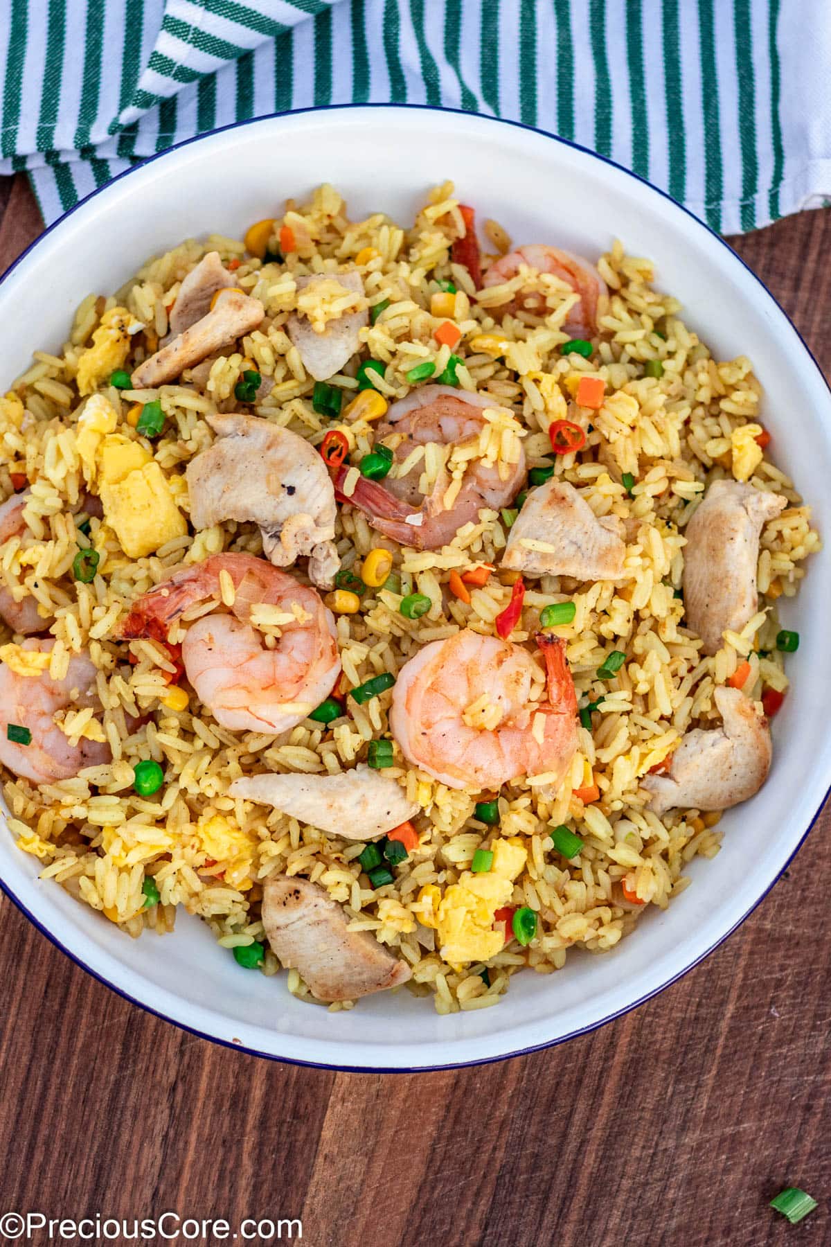 Fried rice in a plate, topped with chicken and shrimp.