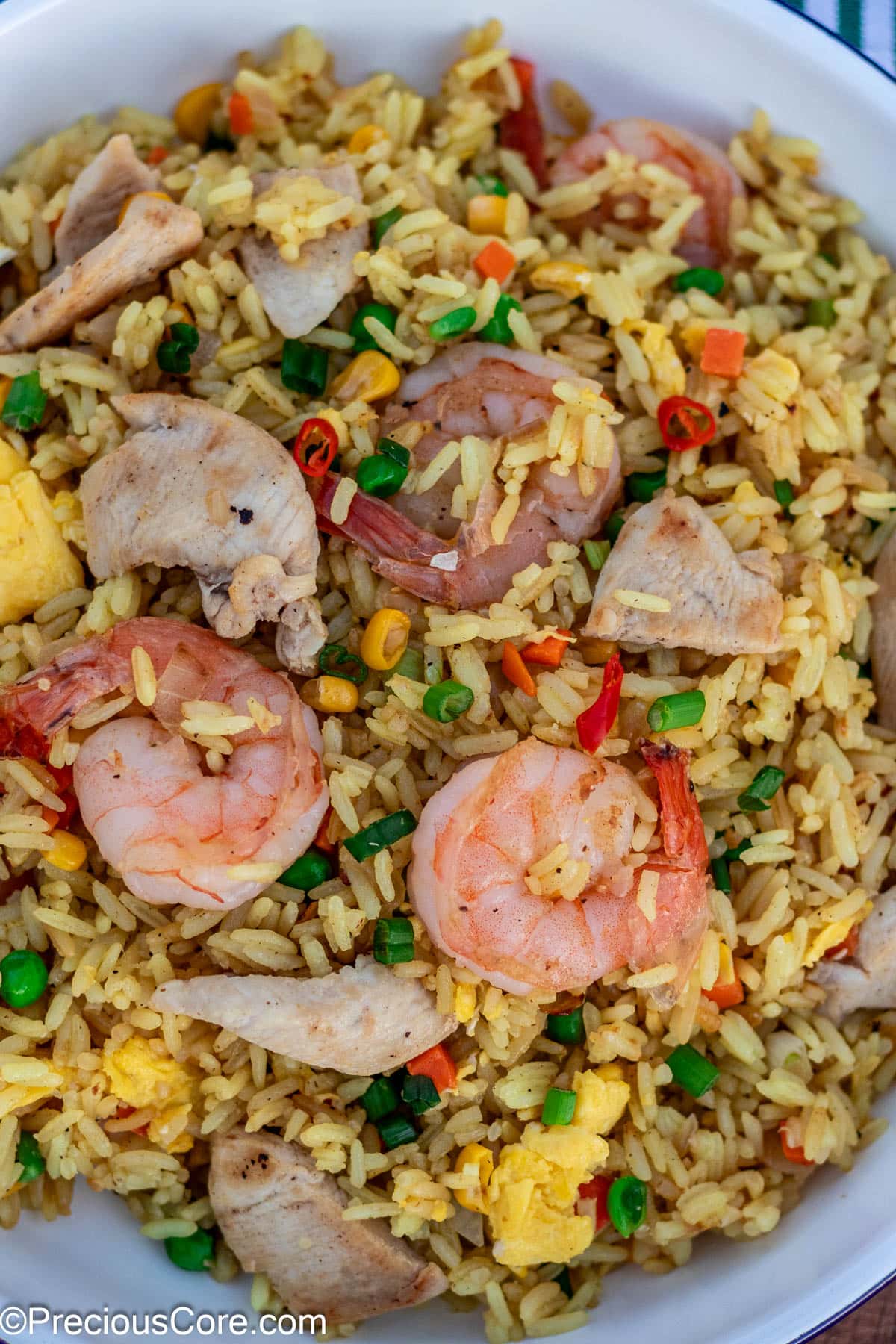 Shrimp and chicken fried rice in a white dish.