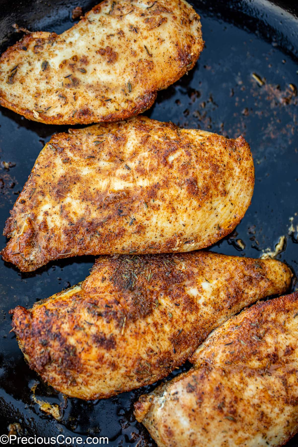 Pan seared chicken breasts in a skillet.