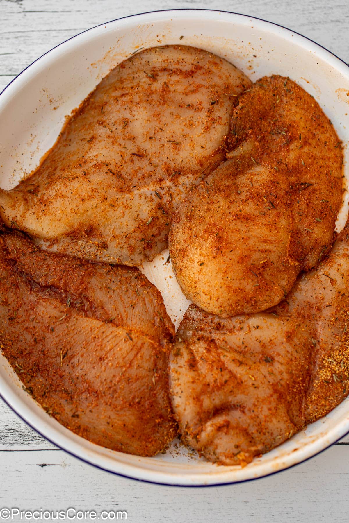 Seasoned chicken breasts in a bowl.