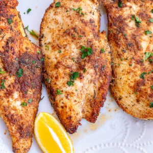 Thin sliced chicken breasts served with lemon wedges.