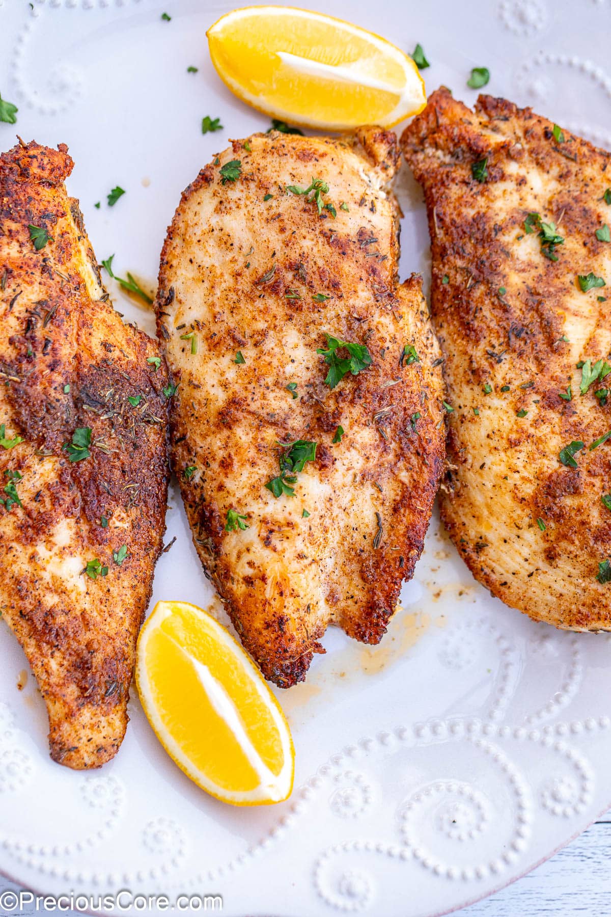 Thin sliced chicken breasts served with lemon wedges.