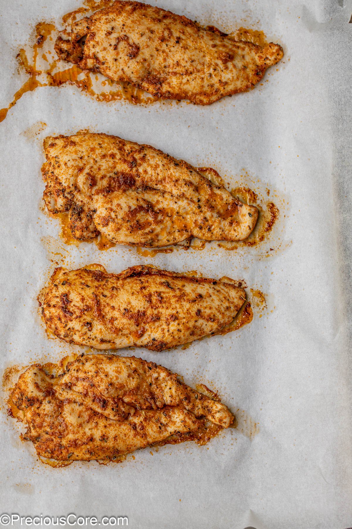 4 sliced of baked chicken breasts on baking sheet.