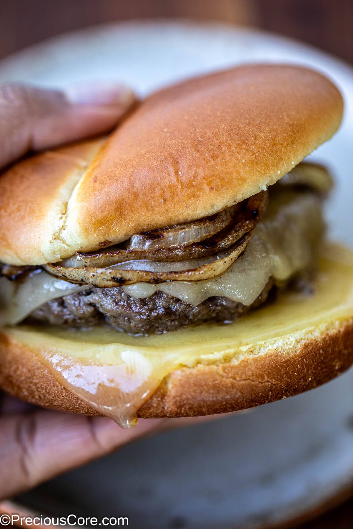 Hand holding a grilled burger.