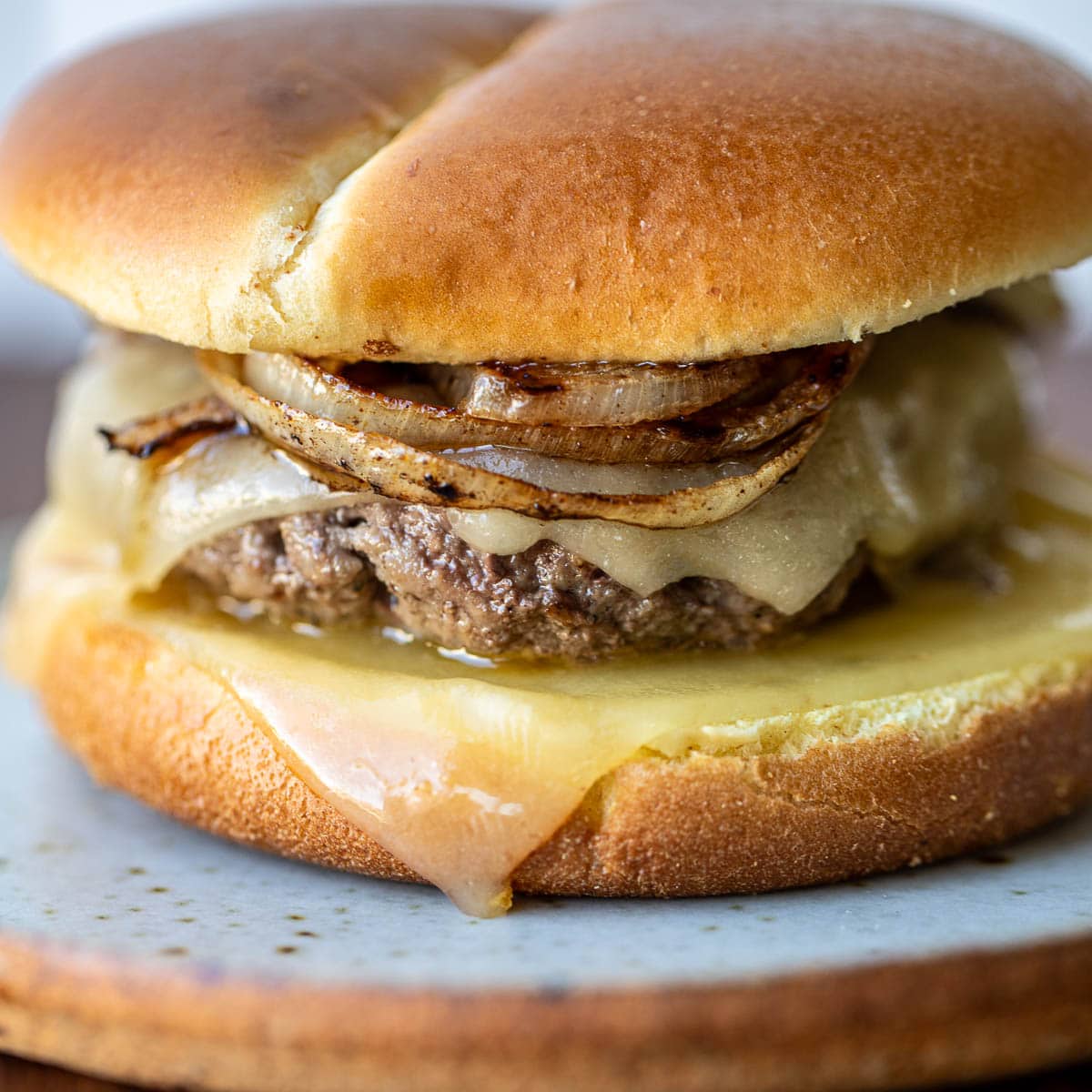 Square image of a grilled onion cheddar burger.