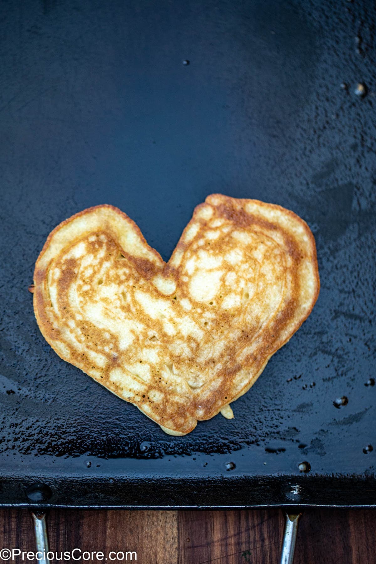 A cooked heart pancake on a griddle.