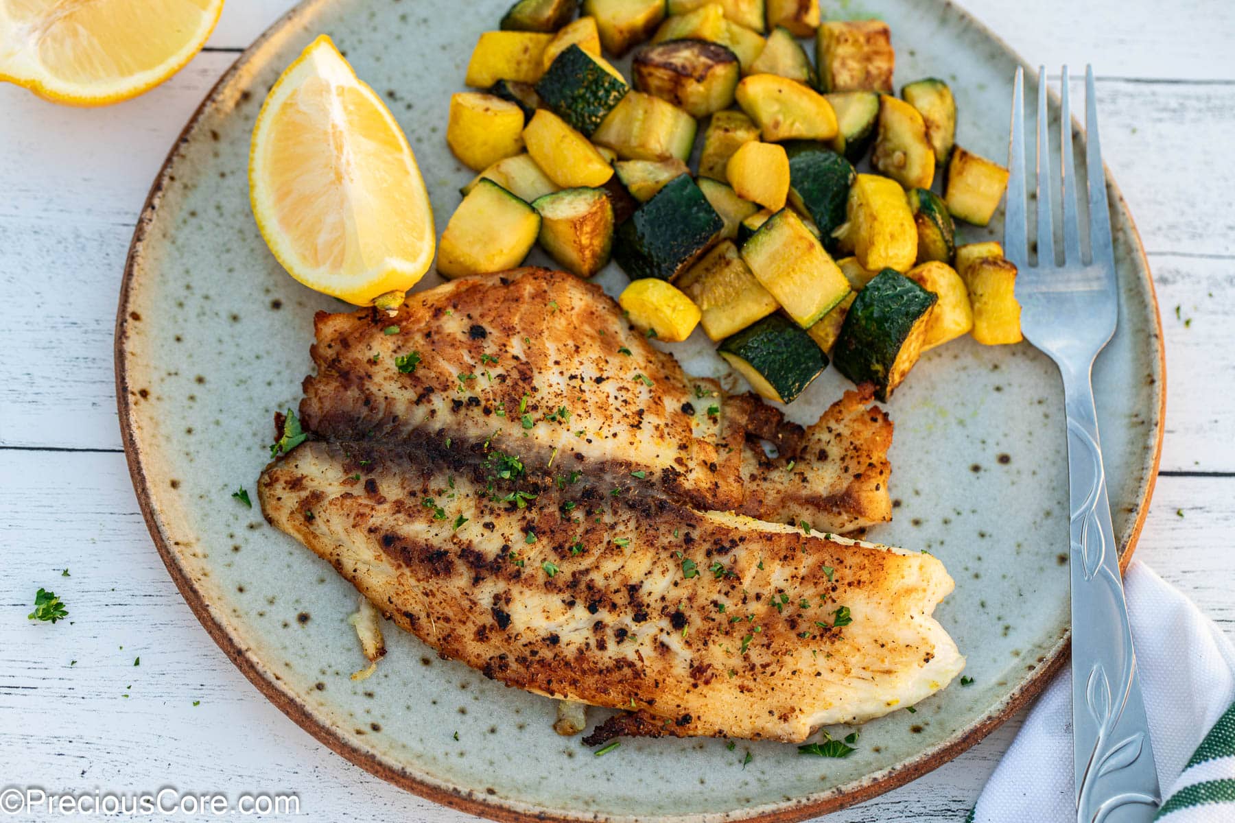 Landscape image of lemon pepper tilapia with vegetables.