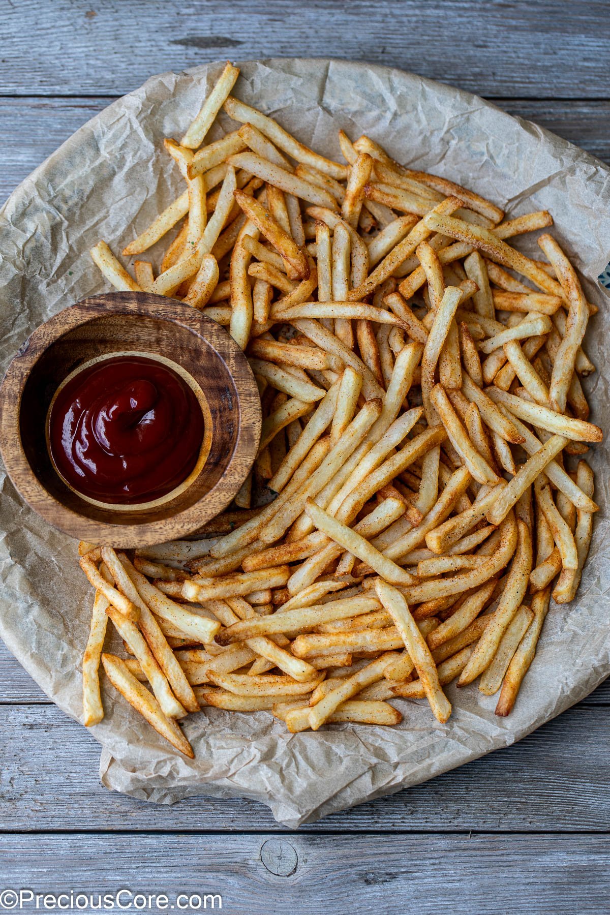Fries on a round serving platter with a bowl of ketchup nearby.