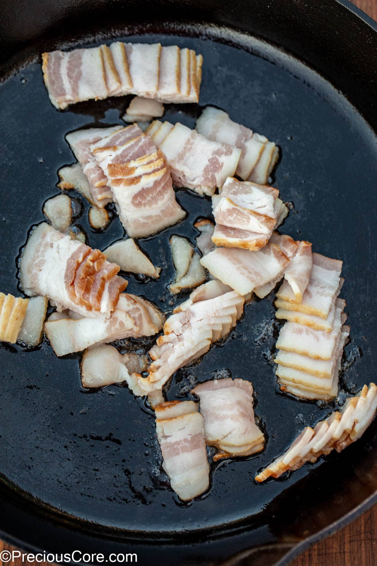 Sliced bacon in a cast iron skillet.