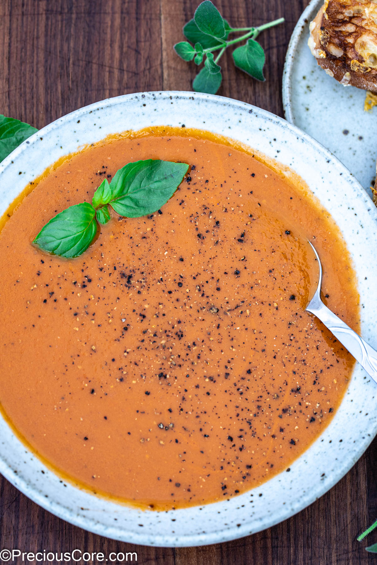 Bowl of tomato soup with black pepper sprinkled on top.