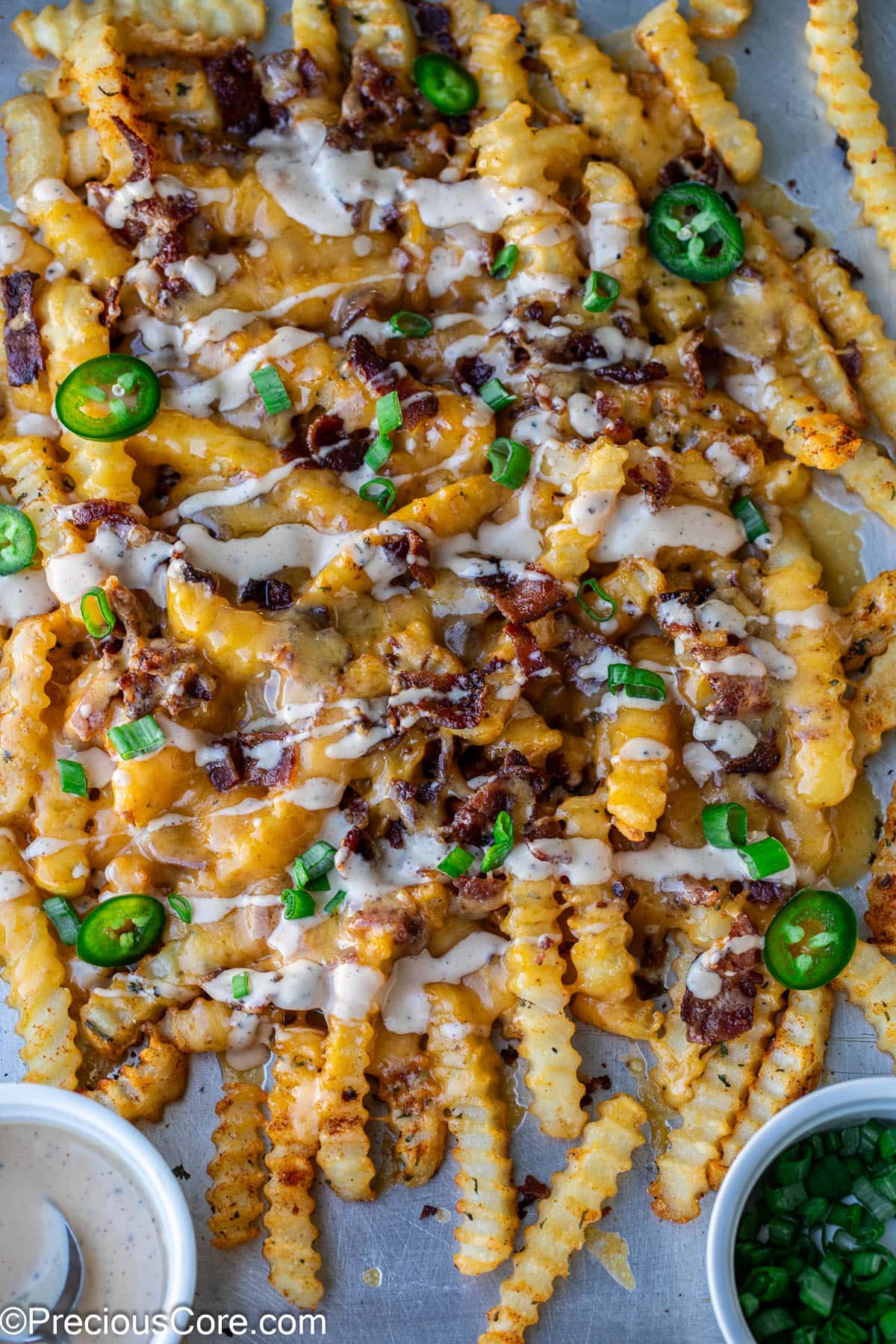 Loaded French Fries on a sheet pan garnished with green onions and sliced jalapenos.