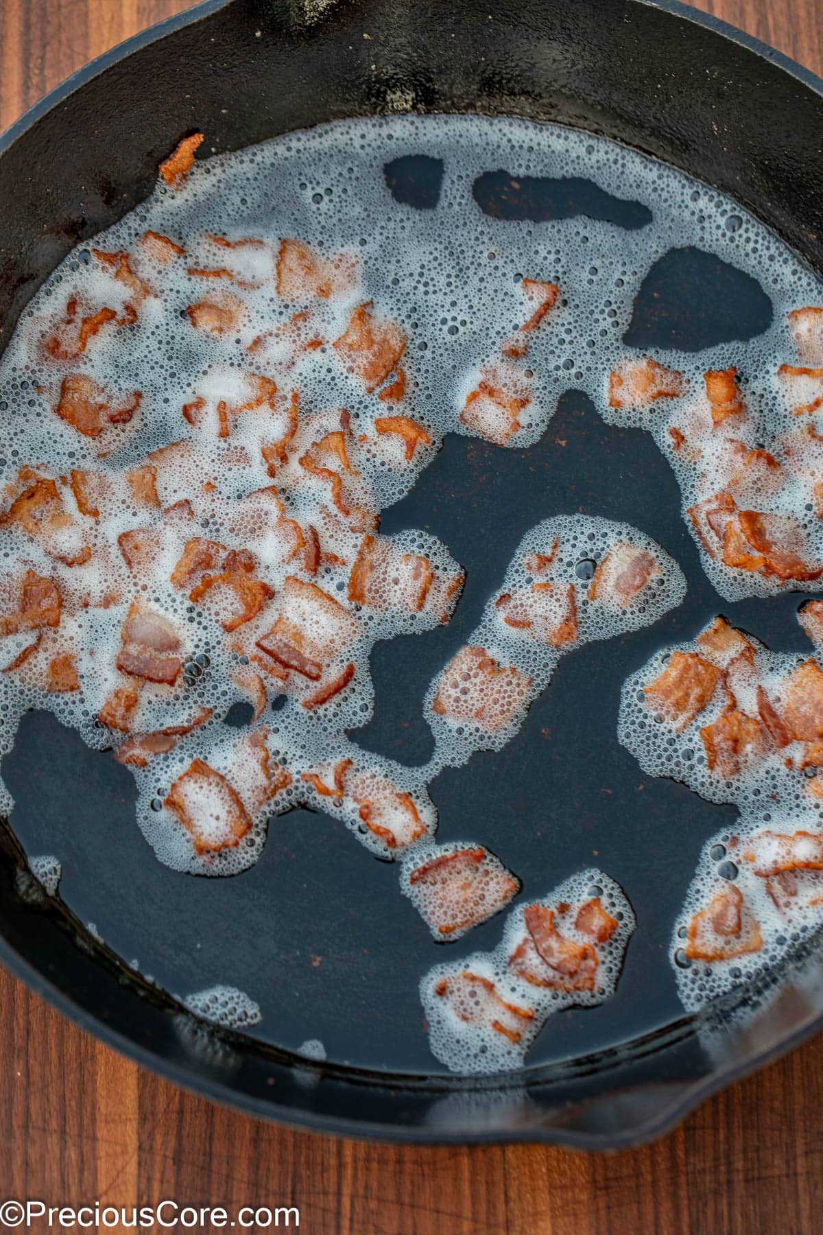Browned bacon bits in bacon grease in a skillet.