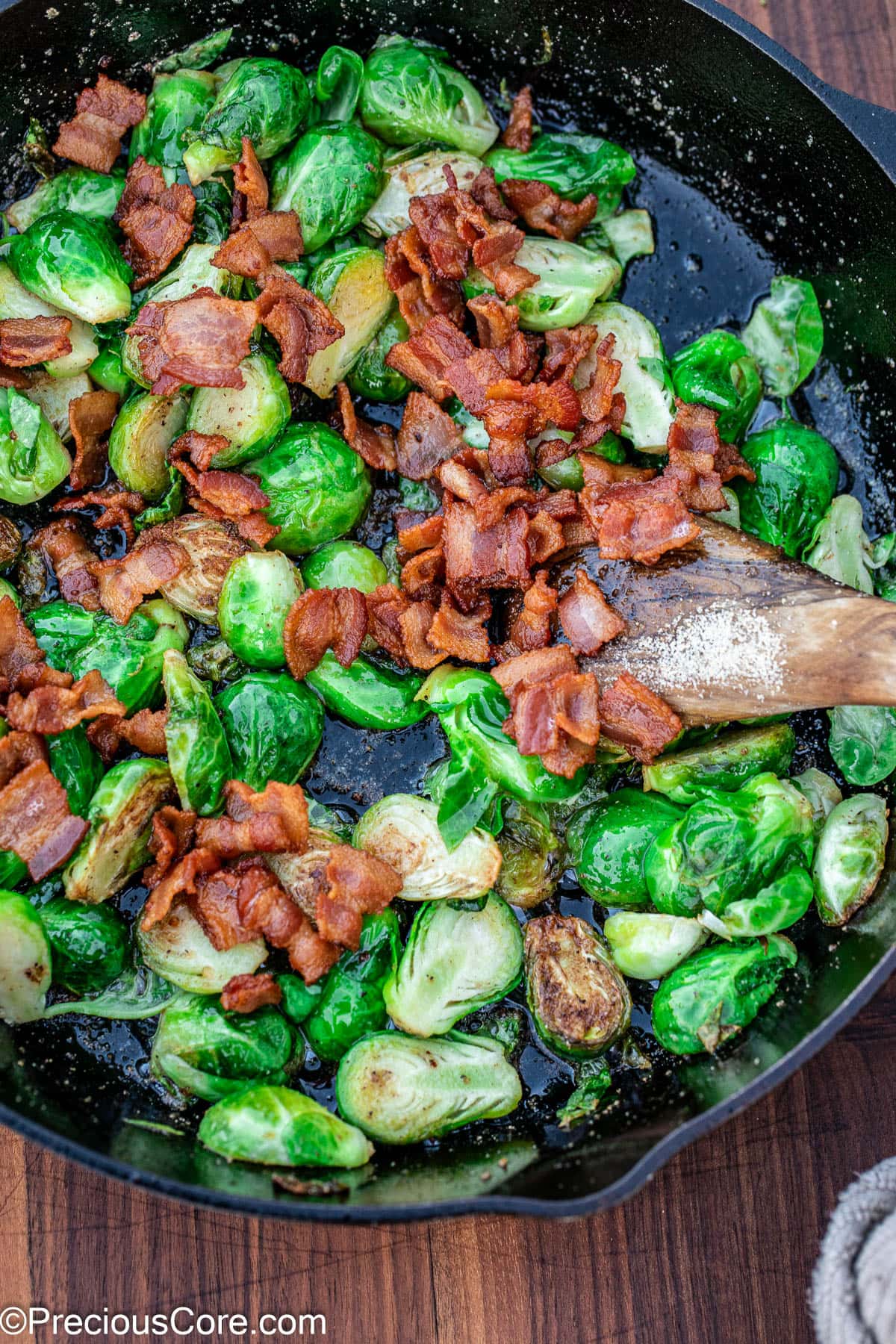 Pan fried Brussels sprouts in a skillet with bacon.