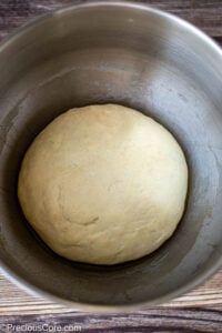 Risen pizza dough in a bowl.