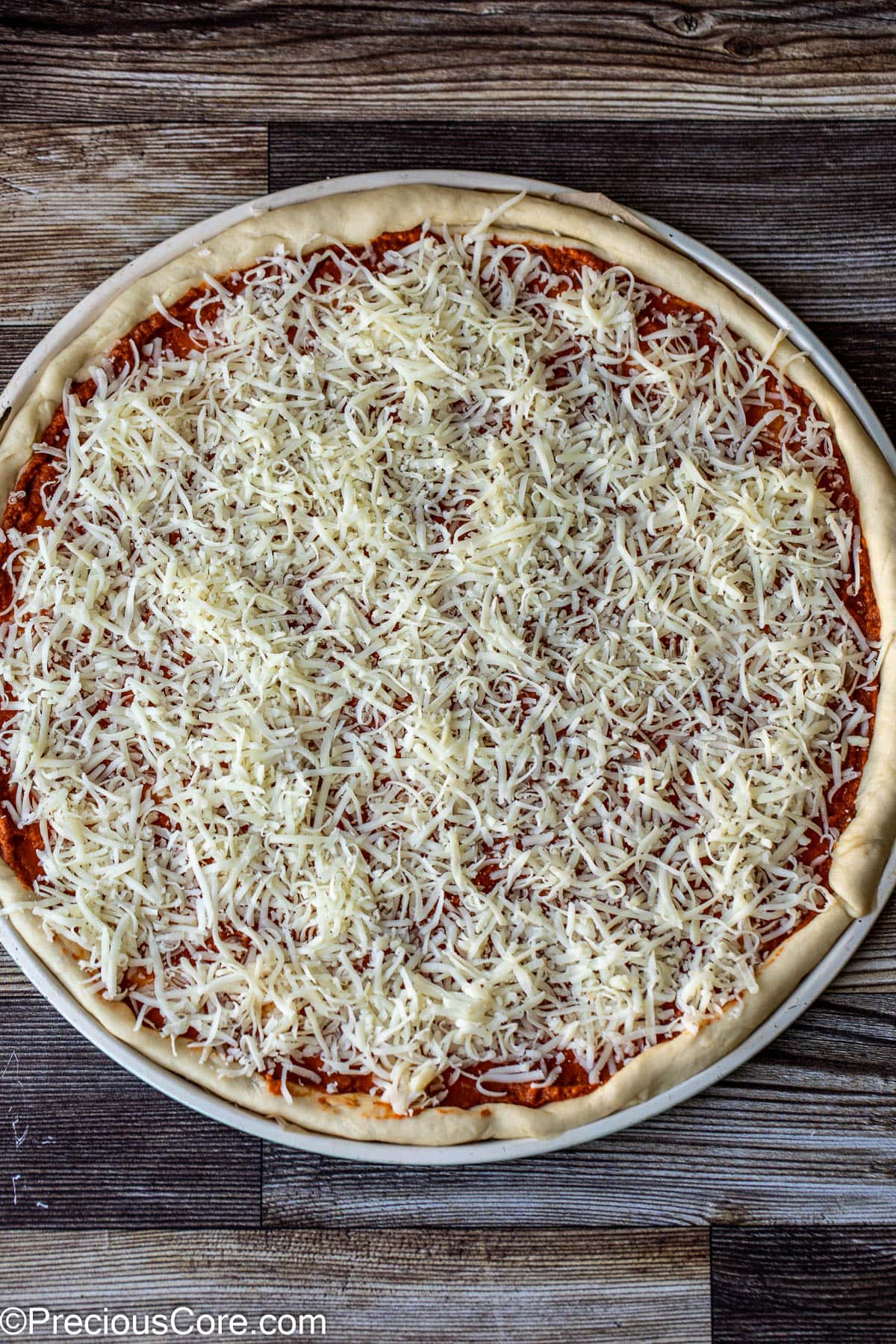 Shredded cheese spread on pizza.