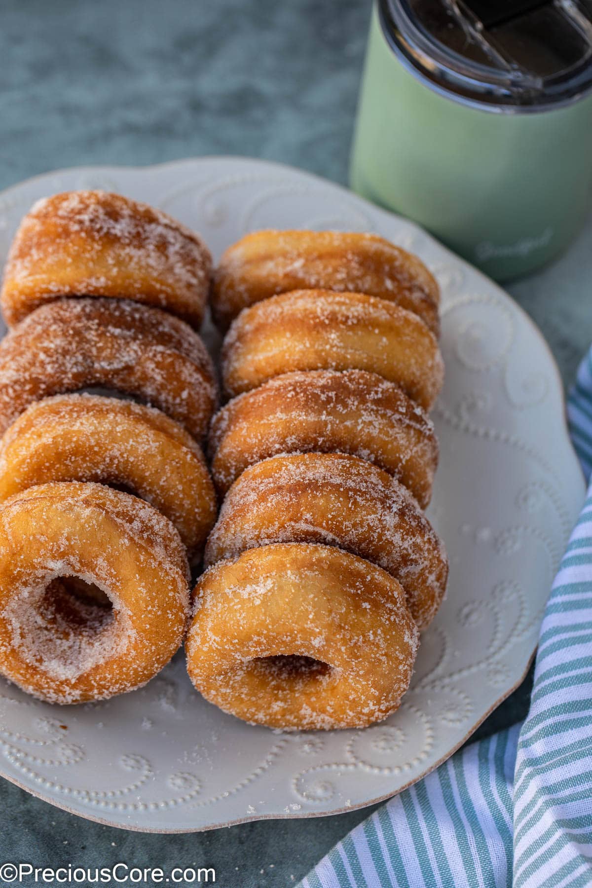 Nine sugar coated donuts on a white plate.